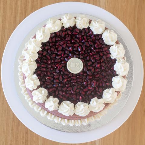 a top down view of the pomegranate gateau with red pomegranate seeds, white chocolate button and white chocolate whipped ganache decoration visible