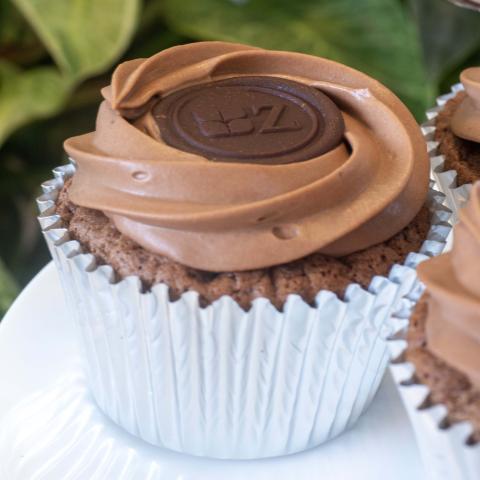 a close up of a dark chocolate Sachertorte-inspired cupcakes decorated with dark chocolate button with the Zuckerhaus logo