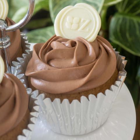 a close up of a chocolate iced Speculaas & Chocolate cupcake decorated with a white chocolate button with the Zuckerhaus logo