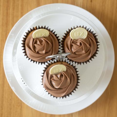 a top down view of three chocolate iced Speculaas & Chocolate cupcaks decorated with white chocolate buttons with the Zuckerhaus logo