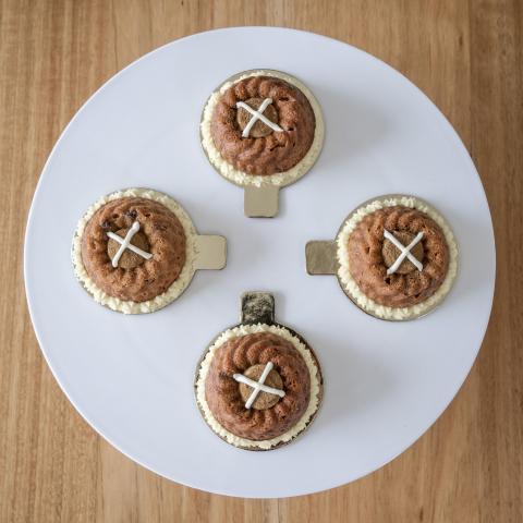 A top down view of four Hot Cross Bundts with visible white crosses on a white cake stand