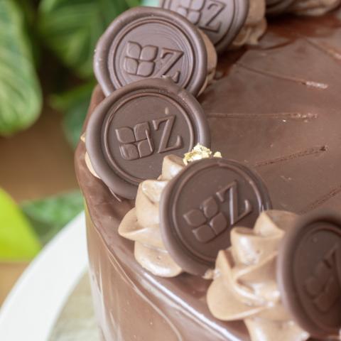 A close up of a chocolate covered prinzregententorte cake with chocolate stamps featuring the Zuckerhaus logo