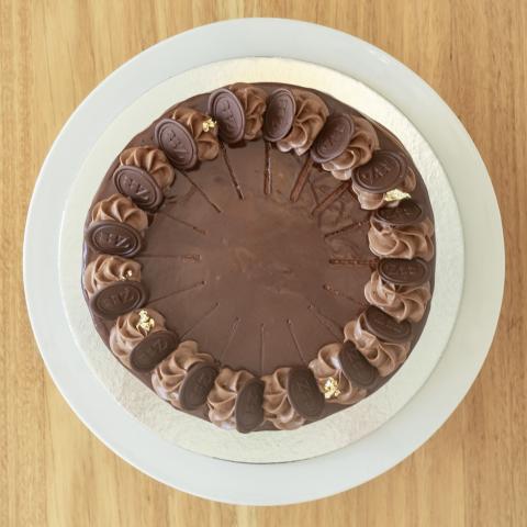 A top down view of a chocolate covered prinzregententorte on a white cake stand